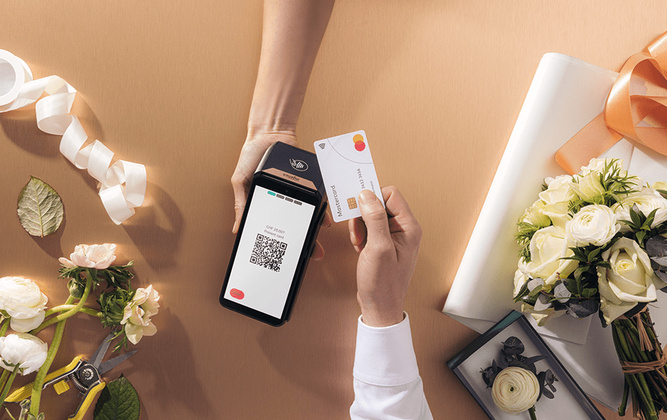 Image depicting a payment terminal showing a QR-code and somebody holder a payment card near the payment terminal